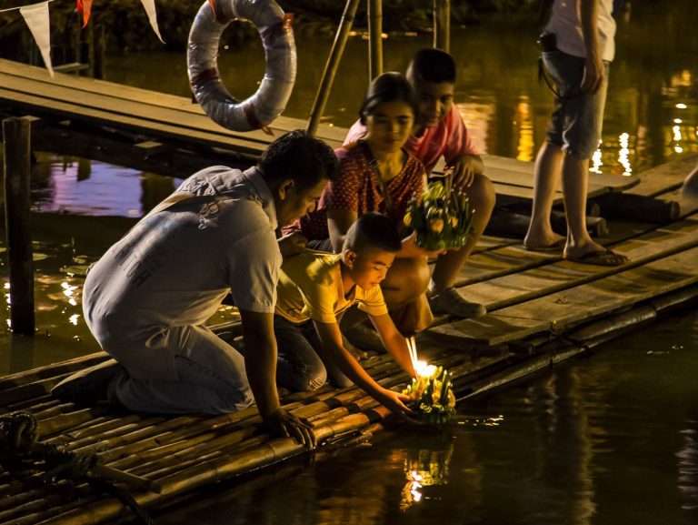 People floating candle-lit krathongs in the Ping River during Loy Krathong