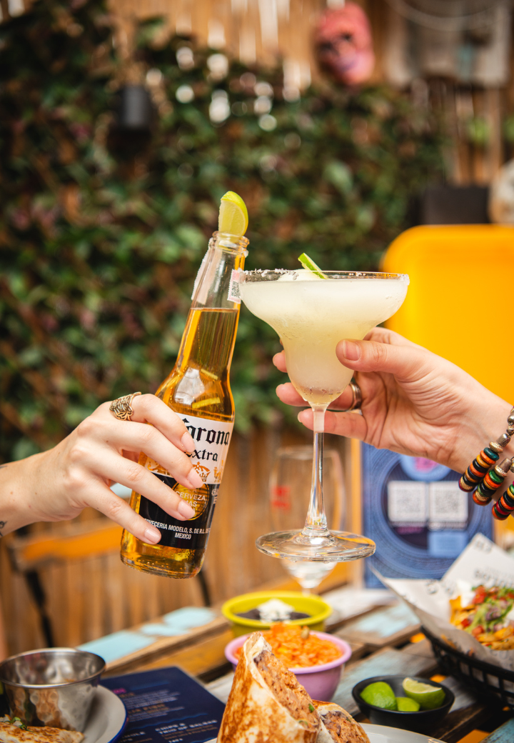Guests raise a beer and margarita over dishes at Cholos