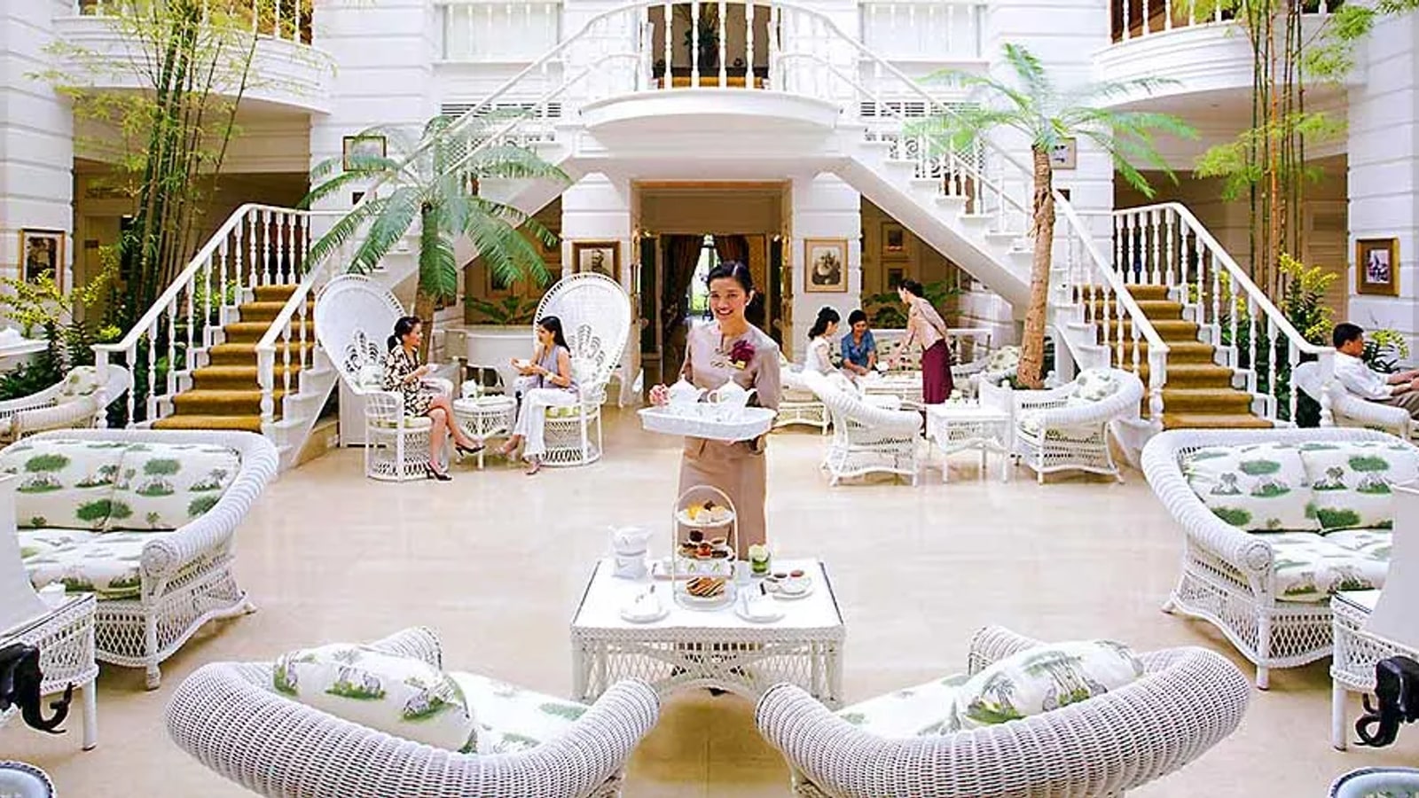 White wicker seating and grand staircase inside The Authors Lounge Bangkok