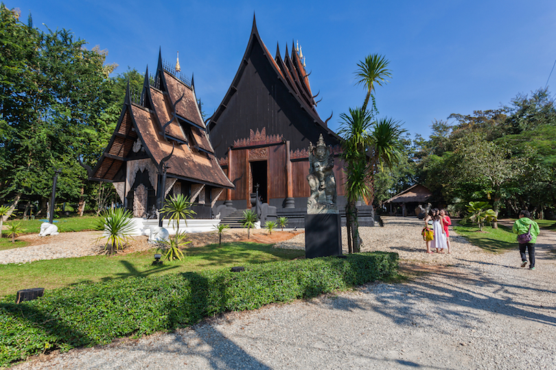Black wooden hall and landscaped grounds at Baan Dam Museum