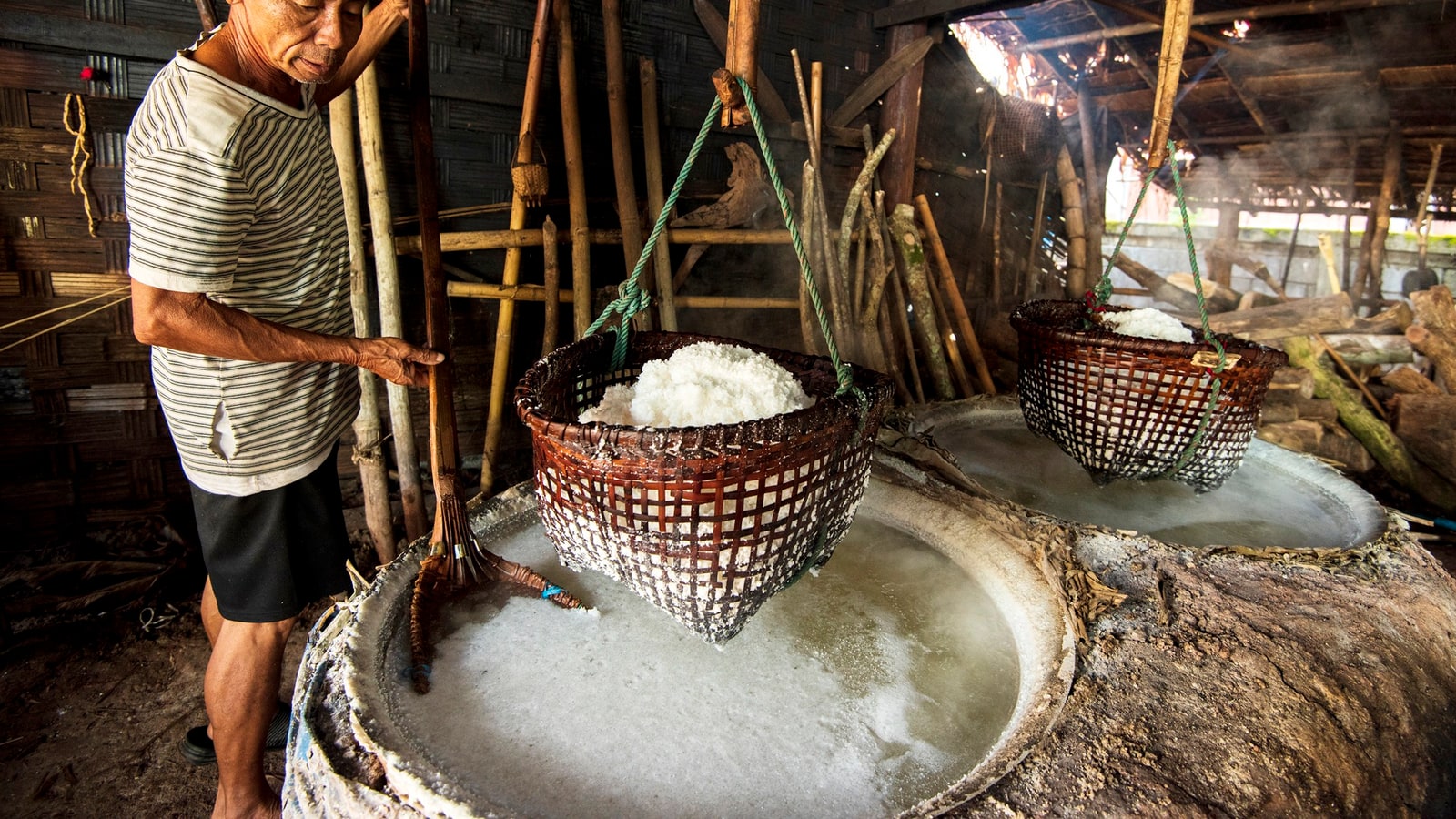 Salt maker lifting a basket of crystals at the Bo Kluea wells
