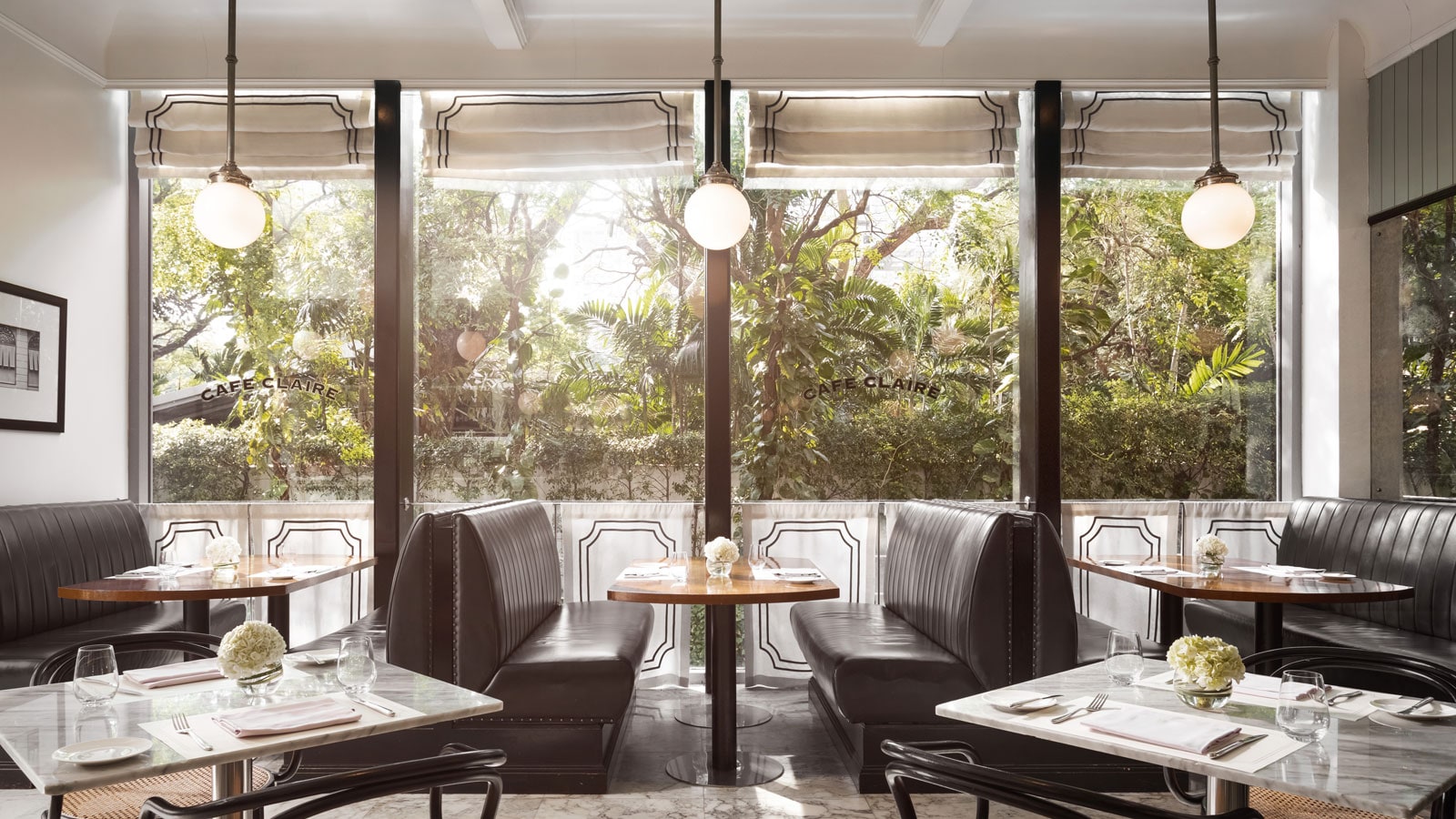 White tables and soft blue seating inside Café Claire