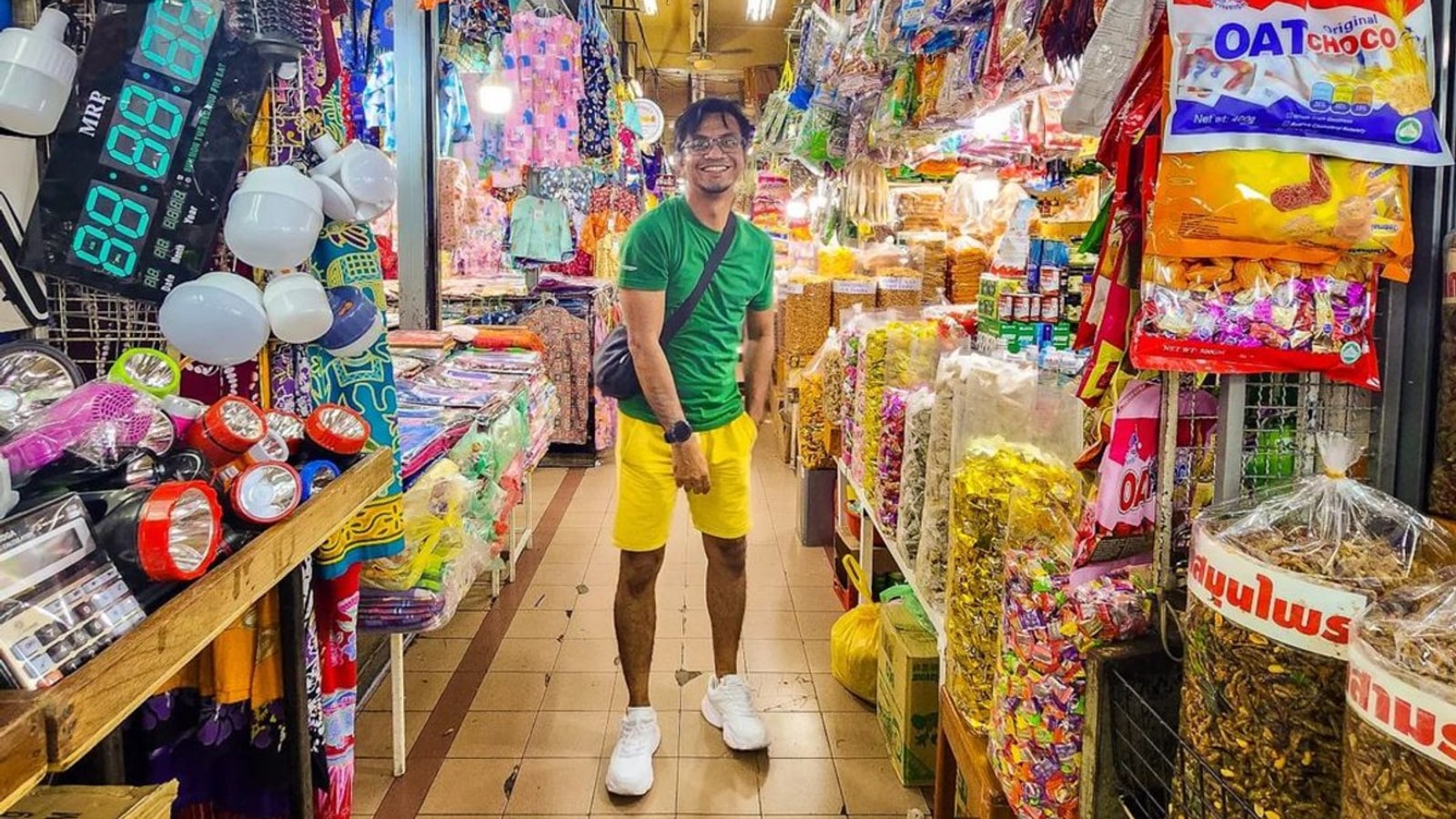Visitor walking through a colourful Kim Yong Market aisle
