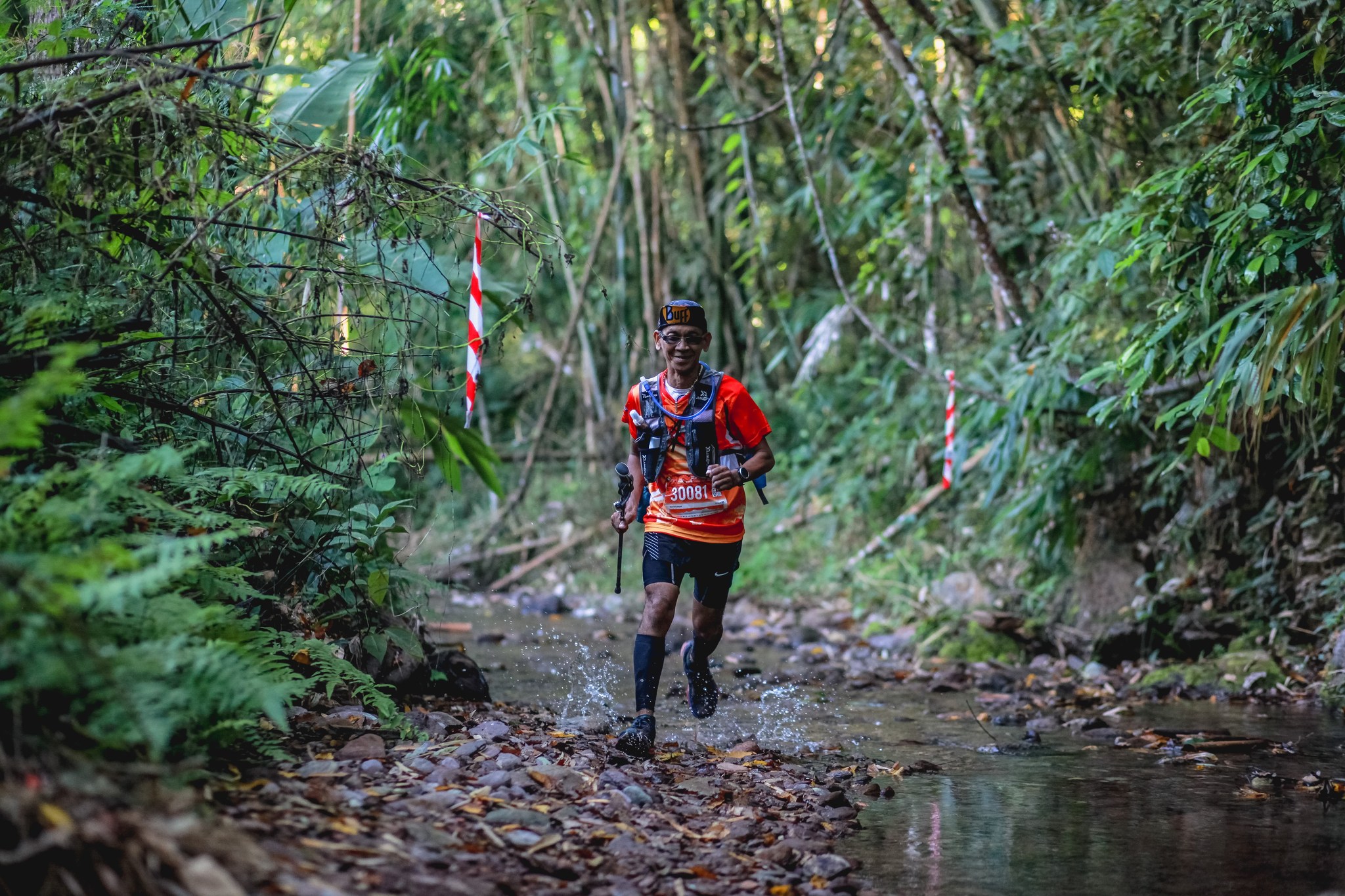 Runner crossing a forest stream at Nan Mountain Trail