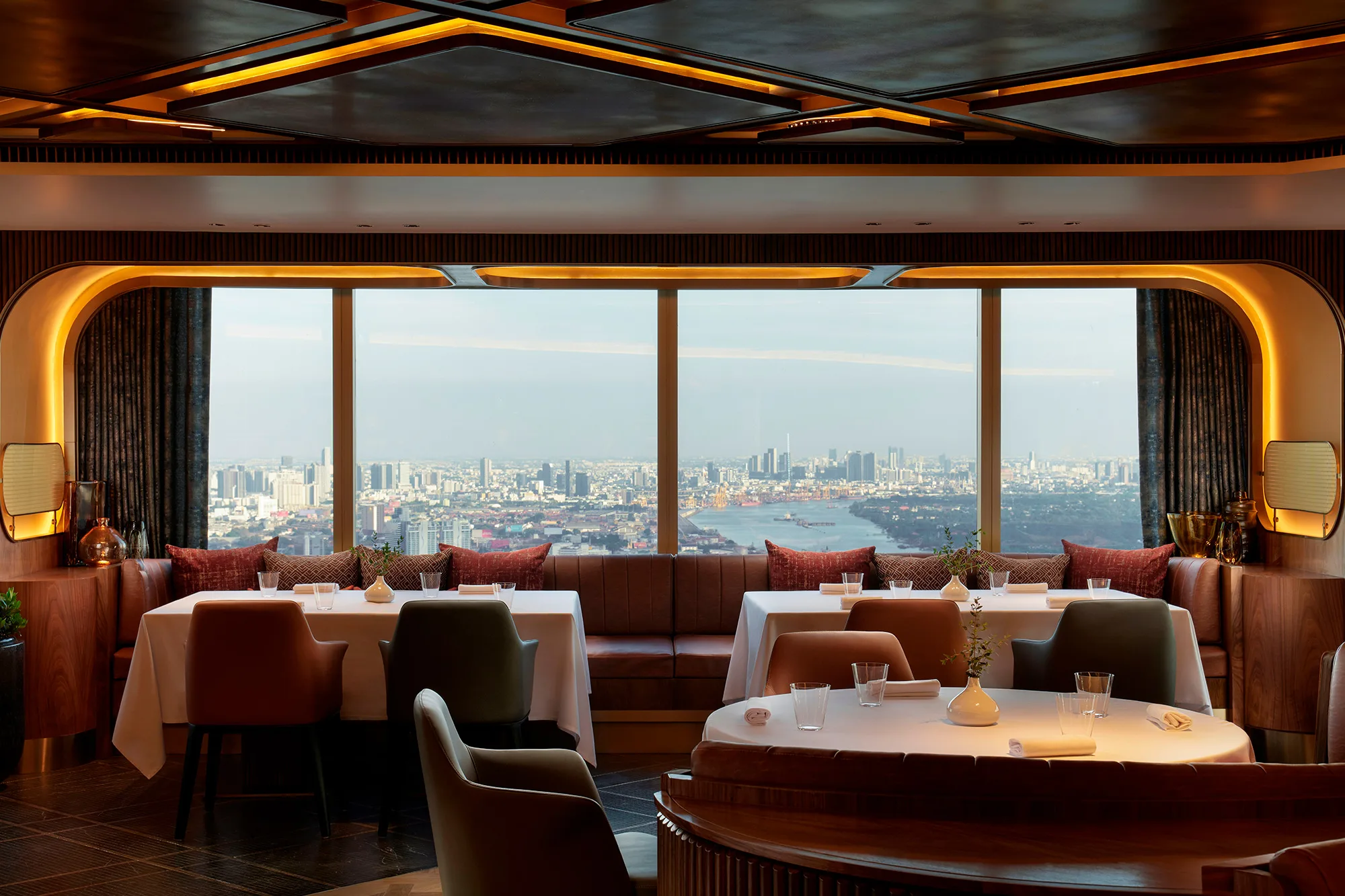 Tables beside panoramic Bangkok windows at Sartoria