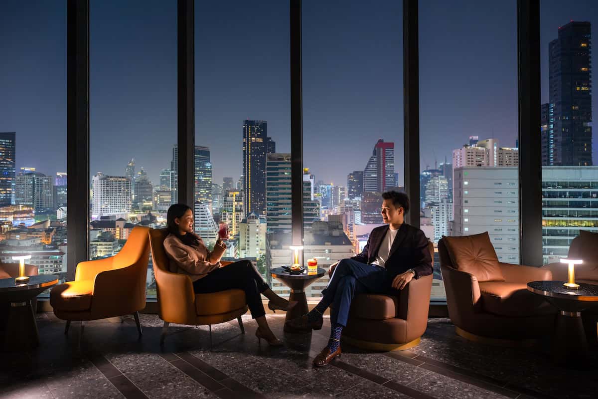Guests seated beside floor-to-ceiling windows at Starlight Rooftop Bar