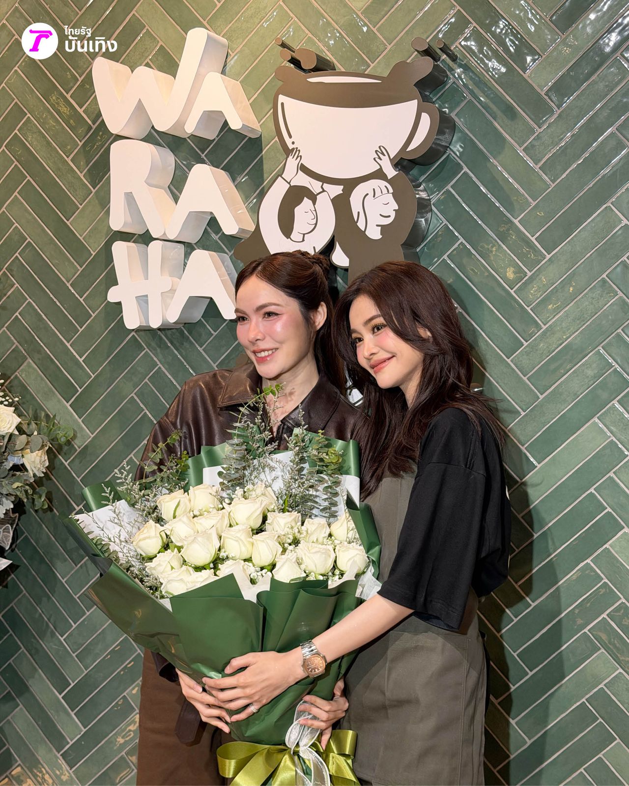 Guests at the Waraha Cafe opening beside its logo wall